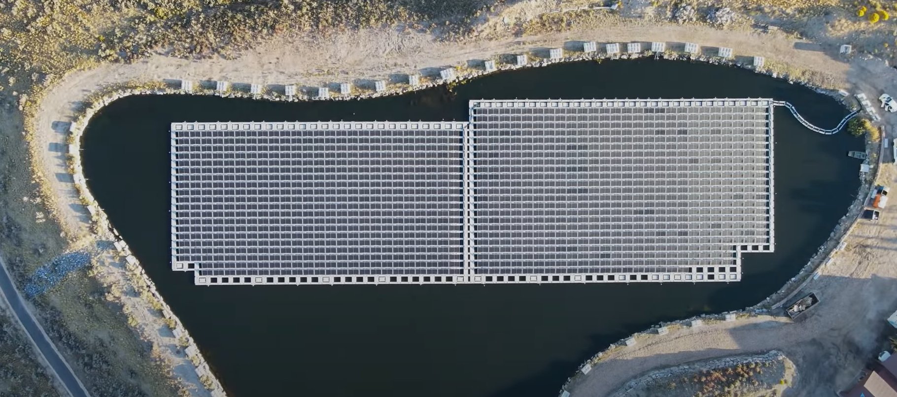Aerial view of a floating solar array covering most of a pond
