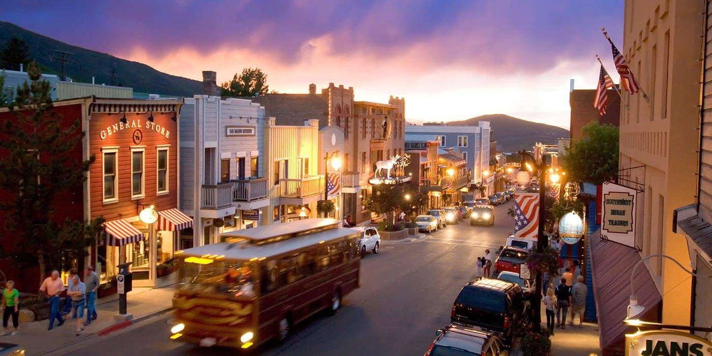 Historic Main Street in Park City, Utah, at sunset, with a trolley passing storefronts