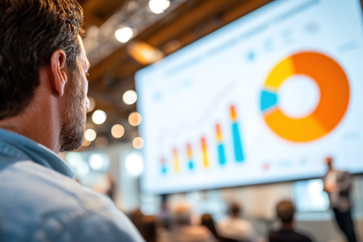 An attendee watching a presentation of charts on a large screen