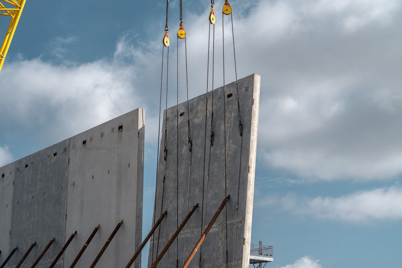 Crane lifting a tilt-up concrete wall panel into place