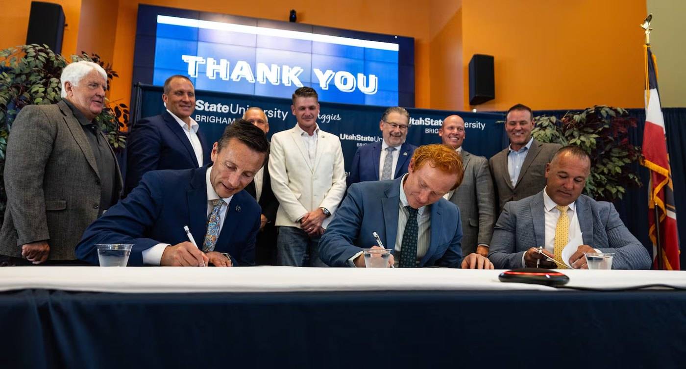 Leaders signing an agreement at a table, with others standing behind